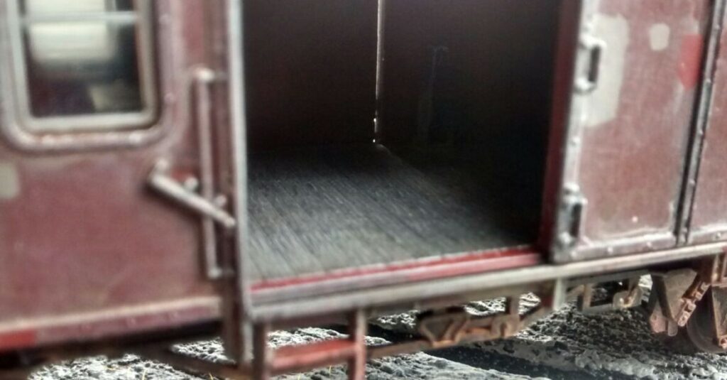 Im Innenraum des Güterwagens wird der Boden des Frachtraums mit Beige trockengebürstet.