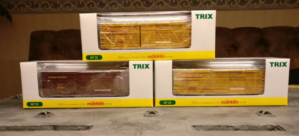 Das Trix 24905 US-Viehwagen-Set Union Pacific in seinen Schachteln. Zwo gelbe und ein braunes LIve Stock Car / Cattle Car der Union Pacific sind zu sehen.