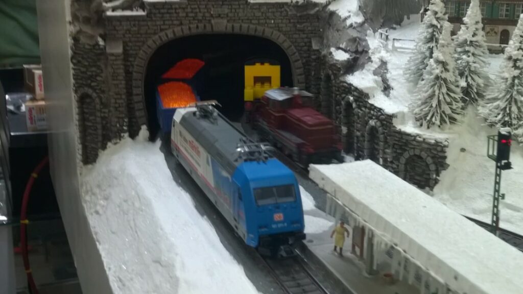 Die Märklin 39374 Elektrolokomotive BR 101 071-9 zieht die drei Märklin 44818 Offener Güterwagen Jim Knopf Lavawagen aus dem Tunnel der Märklin Schaufensteranlage.