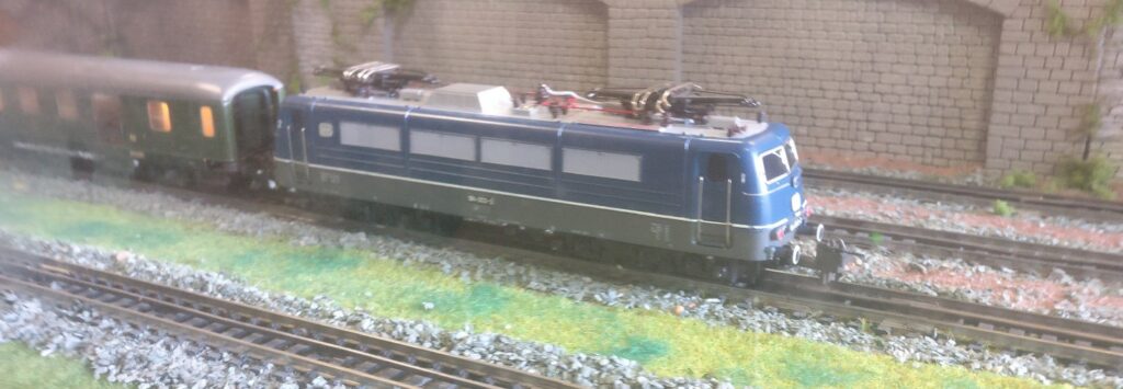 Die Baureihe 184 von der Seite.  Sie zieht einen D-Zug auf der Trix Modellbahnanlage.