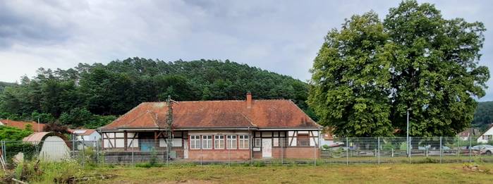 So zeigte sich mir der Bahnhof Hinterweidenthal Ort, als ich vom Teufelstisch herniederfuhr. Man erkennt unschwer den Bauzaun, welcher den Bahnhof von dem davor dem liegenden Gelände des Sägewerks abtrennt. Links auch gut zu sehen, das ominöse Gebäude mit geschwungenem "bayrischen" Dach, das der Versorgung der Dampflokomotiven mit Wasser gedient haben soll.