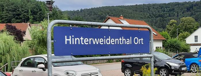 Recht modern: das Namensschild des Bahnhofs Hinterweidenthal Ort.