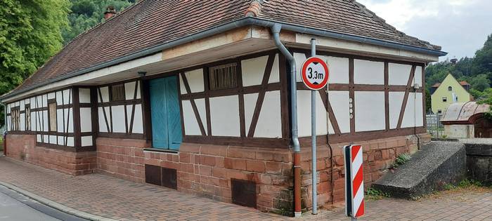 Der integrierte Güterschuppen des Bahnhofs Hinterweidenthal Ort. Die blauen Rolltore künden von früher geschäftigem Verladebetrieb.