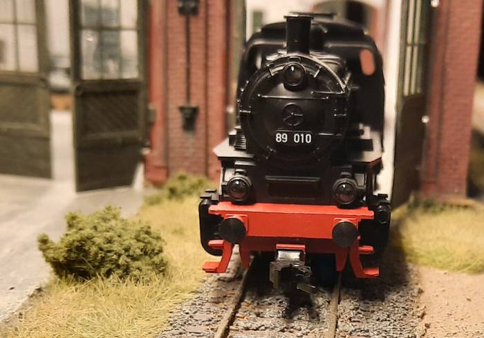 Rückwärts drückt die Märklin 30000 Dampflokomotive BR 89 010 der DB die Waggons in die Produktionshalle.